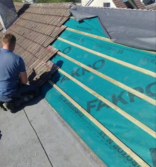 Roofer fitting breathable membrane during a re-roof in Evington