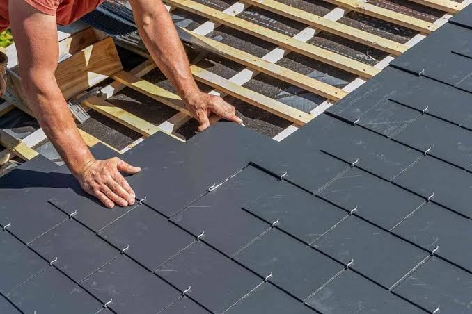 Close-up of hands installing slate roof tiles